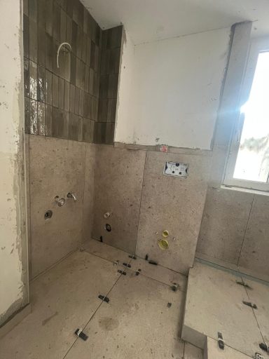 Unfertiger Duschbereich mit Fliesen und Armaturen in einem Badezimmer.